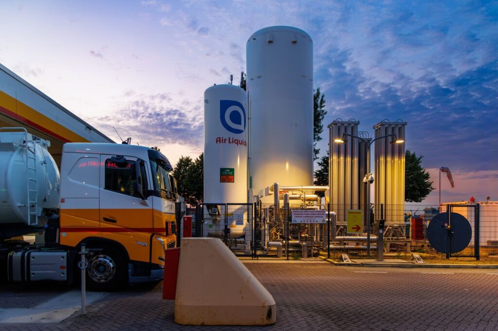A vibrant sunset over a fueling station with tanks and trucks in Rotterdam, Netherlands.